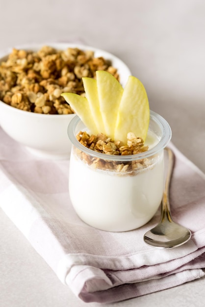 Hausgemachter Joghurt mit Müsli, verziert mit Apple Gesunde Ernährung Frühstücksserviettenlöffel Vertikal