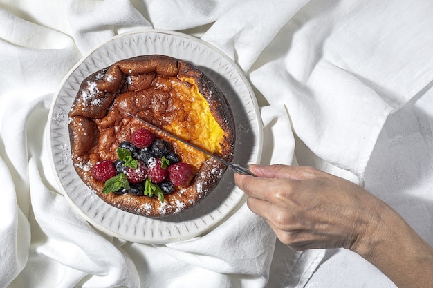 Hausgemachter Käsekuchen mit Blaubeeren, Johannisbeeren, Erdbeeren und Minzblättern von oben. Flach liegen