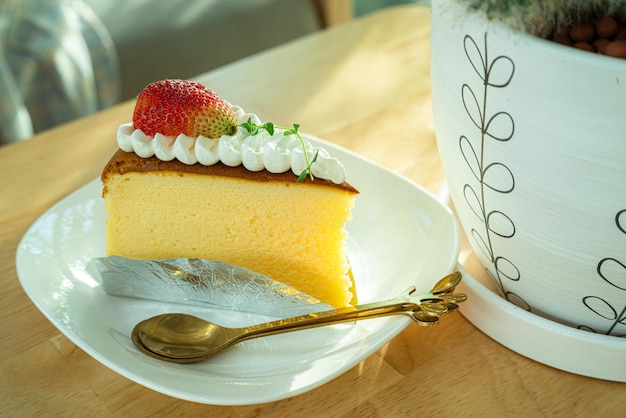 Hausgemachter Käsekuchen mit Erdbeeren auf Teller im Holzschreibtisch Schreibtisch im Café im Café im Garten während der Geschäftsarbeit