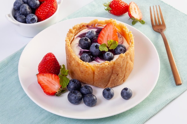 Hausgemachter Käsekuchen mit frischen Erdbeeren und Heidelbeeren auf dem Tisch