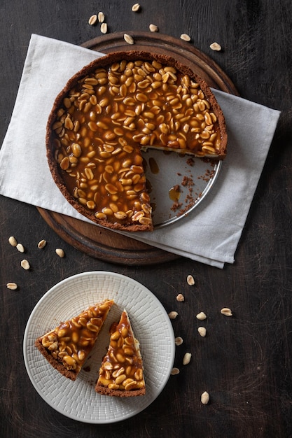 Hausgemachter Karamell-Erdnuss-Käsekuchen auf dunklem Hintergrund Köstlicher Backkuchen am Morgen