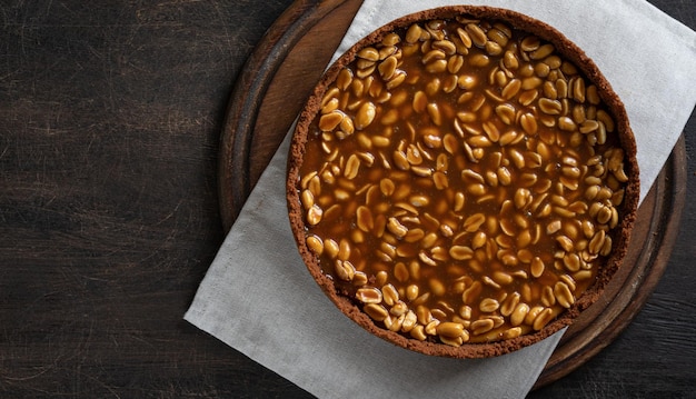 Hausgemachter Karamell-Erdnuss-Käsekuchen auf dunklem Hintergrund Köstlicher Backkuchen am Morgen