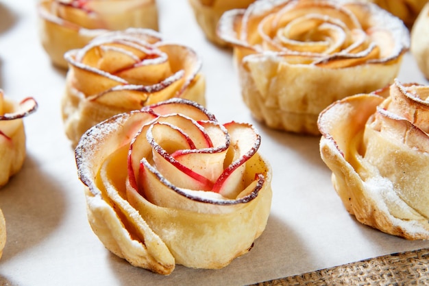 Hausgemachter Keks mit Äpfeln in Form von Rose auf Backpapier. Nahansicht. Geringe Schärfentiefe