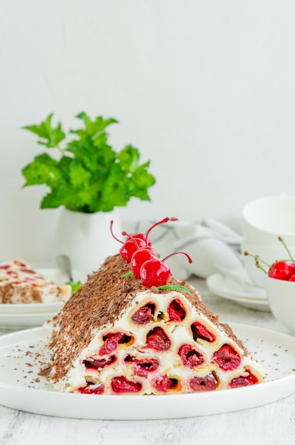 Hausgemachter Kuchen mit Kirschen, Sauerrahm und Schokolade auf einem weißen Teller