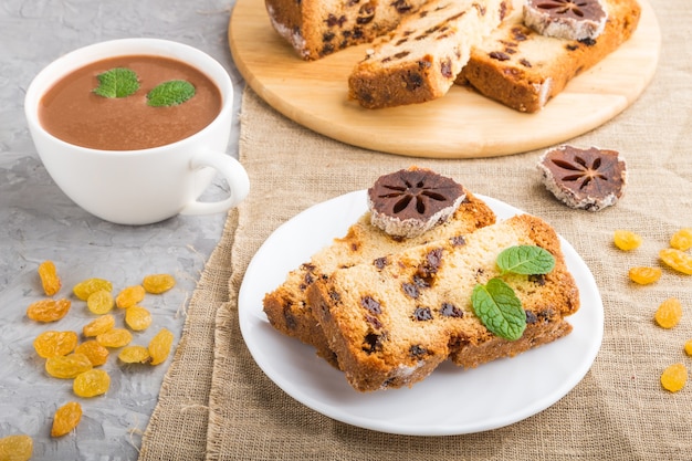 Hausgemachter Kuchen mit Rosinen, getrockneter Kaki und einer Tasse heißer Schokolade