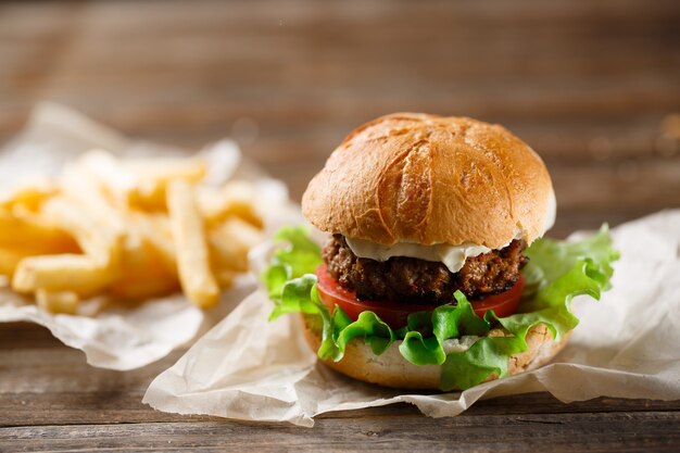 Hausgemachter leckerer Burger und Pommes Frites auf Holztisch