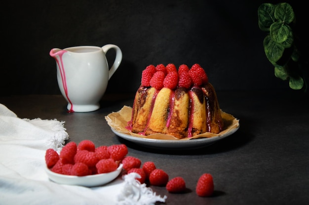 Hausgemachter Marmorkuchen mit Zuckerglasur und Himbeeren auf dunkelgrauem Hintergrund