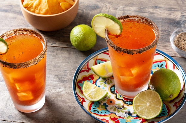 Foto hausgemachter michelada-cocktail mit bier-limettensaft, scharfer soße, salzrand und tomatensaft