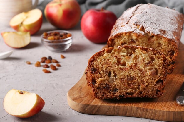 Hausgemachter Muffin mit Äpfeln und Rosinen auf einem Holzbrett auf grauem Hintergrund, Nahaufnahme, Textfreiraum