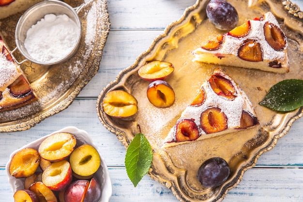 Hausgemachter Pflaumenkuchen in Vintage-Platte auf Holztisch. Pflaumenkuchen mit Zuckerpulver.