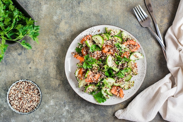 Hausgemachter Salat aus Gurken, Tomaten, Quinoa-Mix und Kräutern auf einem Teller auf dem Tisch Vegetarisches Essen Draufsicht