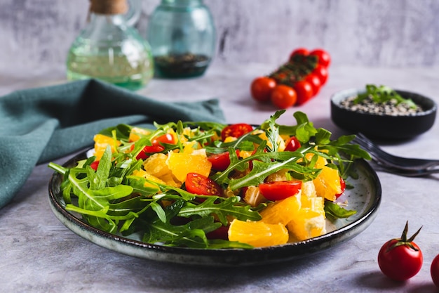 Hausgemachter Salat aus orangefarbenen Kirschtomaten und Arugula auf einem Teller auf dem Tisch