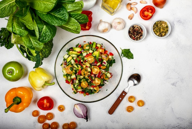 Hausgemachter Salat aus verschiedenen Bio-Gemüsen in einer Glasschüssel mit Zutaten und Gewürzen