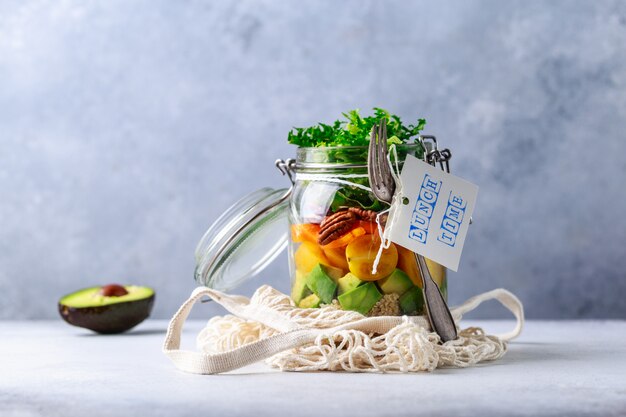 Hausgemachter Salat im Glas mit Quinoa und Gemüse mit Etikett Mittagspause ohne Plastik und Konzept zum Mitnehmen