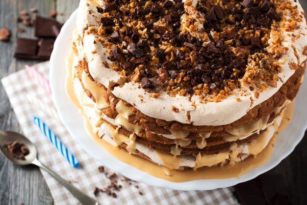 Hausgemachter Schichtkuchen und Baiser, Walnüsse, dunkle Schokolade auf altem Holz