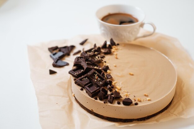 Hausgemachter Schokoladenkuchen auf Pergamentpapier Lieferung von Lebensmitteln Hausgemachtes Backen Draufsicht Köstliche Torte mit Schokolade auf dem weißen Tisch mit einer Tasse Kaffee