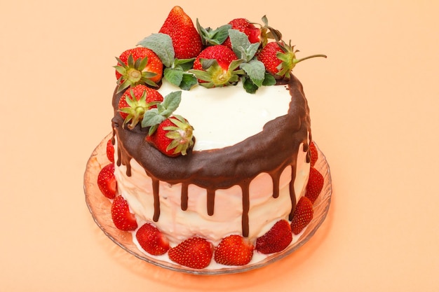 Hausgemachter Schokoladenkuchen mit frischen Erdbeeren auf Glasplatte auf beigefarbenem Hintergrund