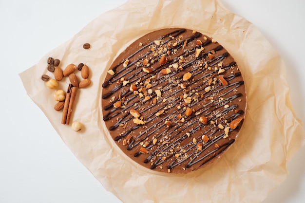 Hausgemachter Schokoladenkuchen mit Nüssen auf Pergamentpapier Lieferung von Lebensmitteln Hausgemachtes Backen Draufsicht Köstliche Torte mit Schokolade und Nüssen auf dem Holztisch