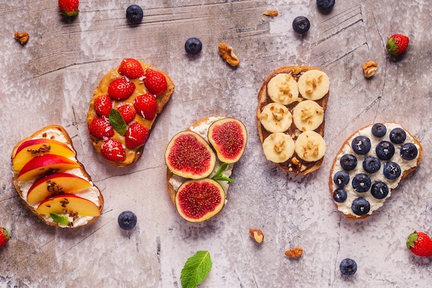 Hausgemachter Sommertoast mit Frischkäse, Nussbutter und Früchten und Beeren, Draufsicht.