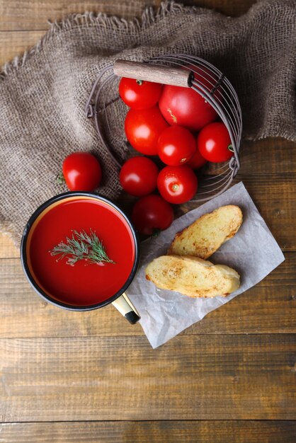 Hausgemachter Tomatensaft in farbigen Bechertoasts und frischen Tomaten auf Holzhintergrund