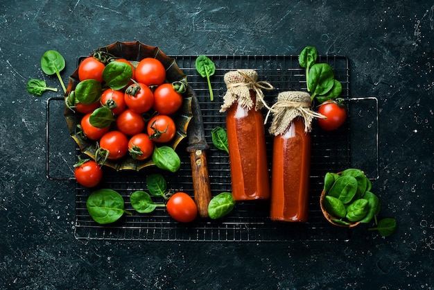 Hausgemachter Tomatensaft in Glasflaschen. Ansicht von oben. Auf einem Steinhintergrund.