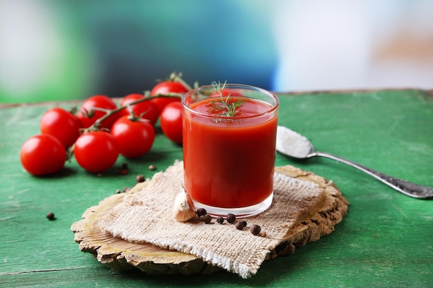 Hausgemachter Tomatensaft in Glasgewürzen und frischen Tomaten auf Holzhintergrund