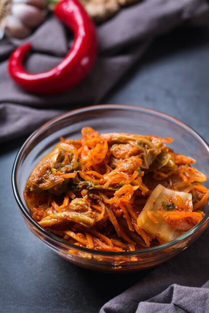 Foto hausgemachter traditioneller koreanischer kimchi-kohlsalat aus biologischem anbau mit stäbchen auf einem dunklen tisch. fermentiertes vegetarisches, vegan konserviertes darmgesundheits-lebensmittelkonzept