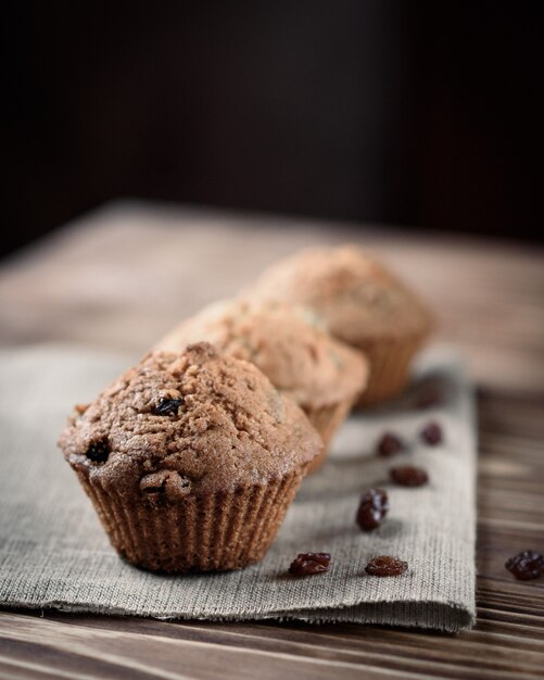 Hausgemachtes Backen: Cupcakes mit Rosinenbonbons auf Leinentuch auf einem hölzernen Hintergrund.