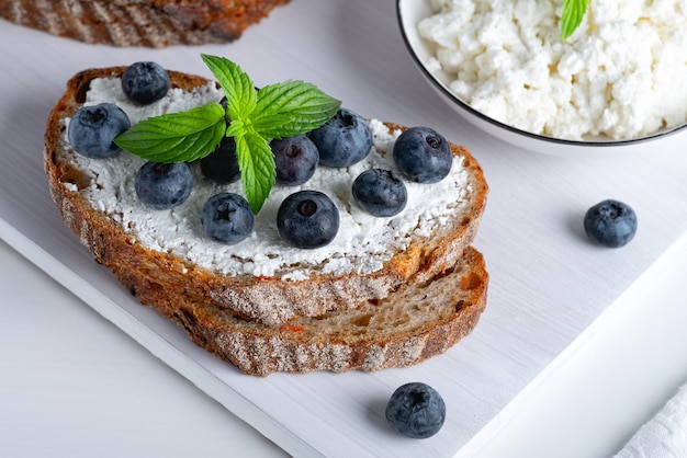 Hausgemachtes Brot auf einem Holzbrett mit Quark und Blaubeeren und Minze