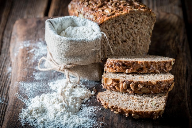 Hausgemachtes Brot mit mehreren Körnern und Mehl im Sack