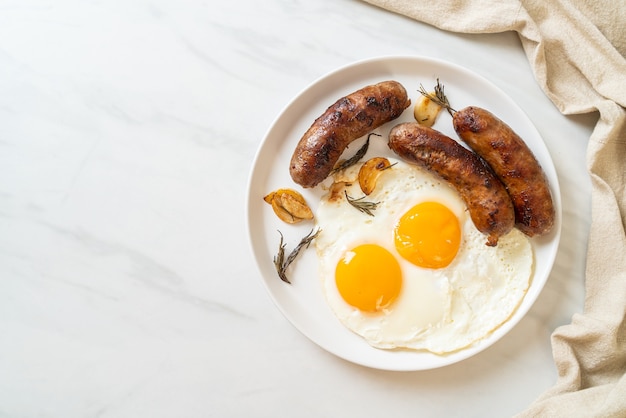 Hausgemachtes doppeltes spiegelei mit gebratener schweinswurst - zum frühstück