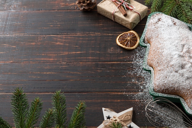 Hausgemachtes Gebäck, weihnachtsbaumförmige Kekse, Geschenke, Fichtenzweige und Dekorationen auf einem Holztisch. Draufsicht.