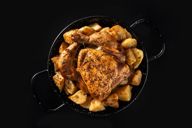 Hausgemachtes gebratenes Huhn mit Kartoffeln auf schwarzem Hintergrund