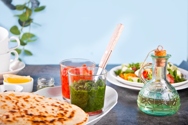 Hausgemachtes indisches Naan-Fladenbrot mit frischem Salat und Dips auf dem Esstisch