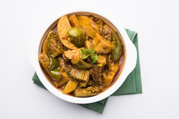 Hausgemachtes indisches würziges Auberginen- und Kartoffelcurry, auch bekannt als Aloo Baigan Ki Sabzi in Hindi, serviert in Kadhai oder weißer Schüssel, selektiver Fokus