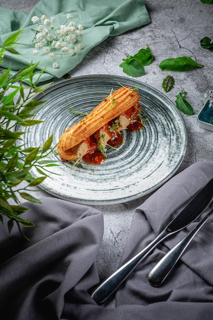 Hausgemachtes Leberpastetensandwich in Croissant mit Microgreens-Salat auf einem Teller auf einem grauen Steintisch. Speisekarte