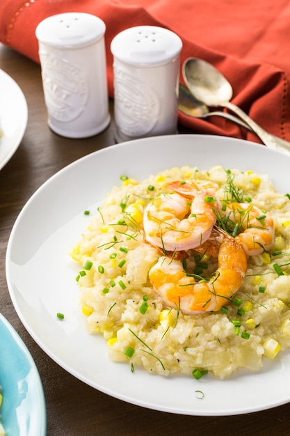 Hausgemachtes Maisrisotto mit gebratenen Garnelen auf dem Esstisch.