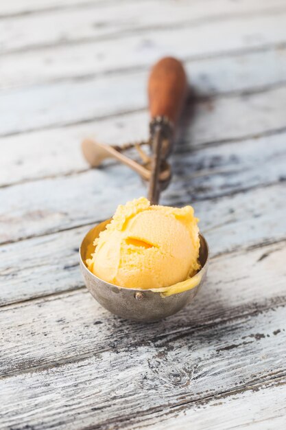 Hausgemachtes Mango-Eis in Schalen mit frischen Früchten auf weißem Holz