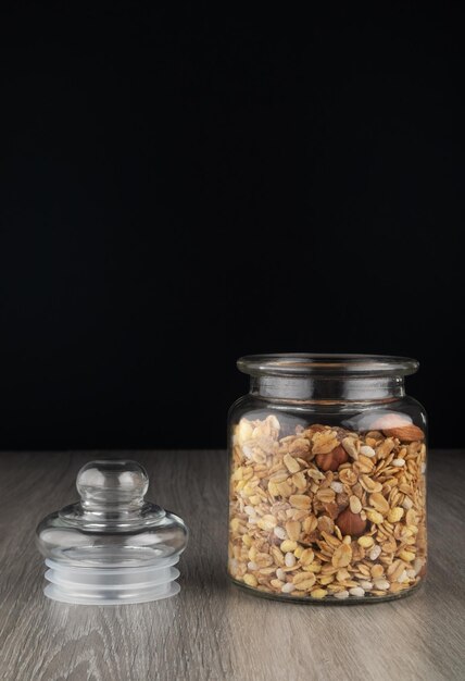 Hausgemachtes Müsli im Glas auf dem Küchentisch. Gesundes Frühstück mit Haferflocken-Müsli und Nüssen