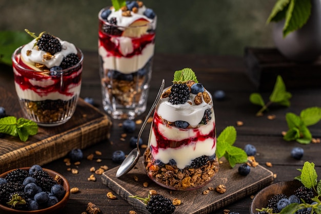 Hausgemachtes Müsli mit griechischer Joghurt-Beeren-Marmelade und frischen Brombeeren und Blaubeeren in Gläsern