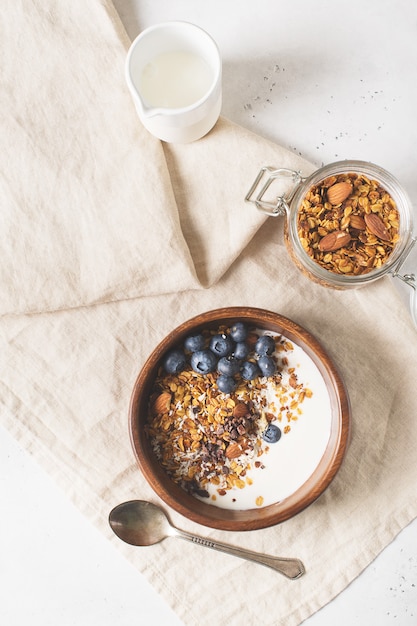 Hausgemachtes Müsli-Müsli mit Blaubeeren auf weißer vertikaler Draufsicht