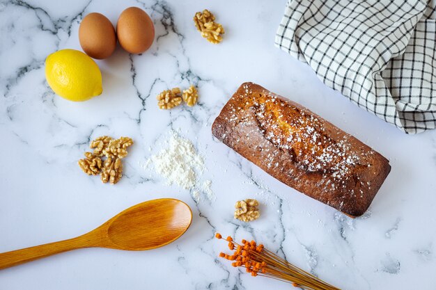 Hausgemachtes Nusskuchen- und Zutatenbackkonzept auf weißem Marmor