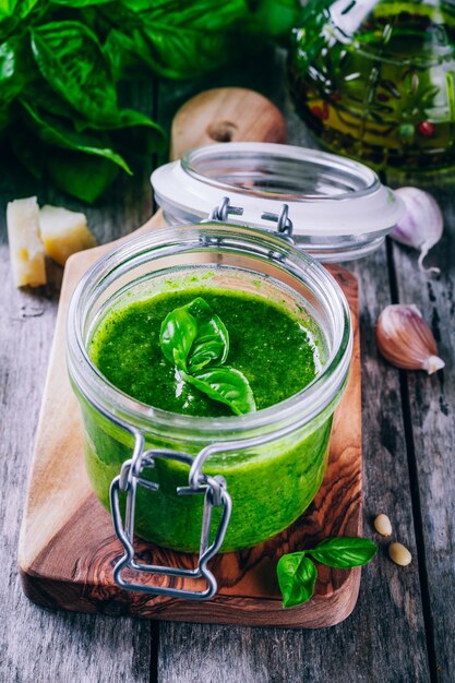 Foto hausgemachtes pesto in einem glasgefäß auf einem hölzernen rustikalen hintergrund