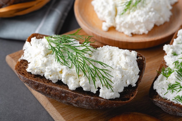 Hausgemachtes Roggenbrot auf einem Holzbrett mit Quark, Ricotta und Dill