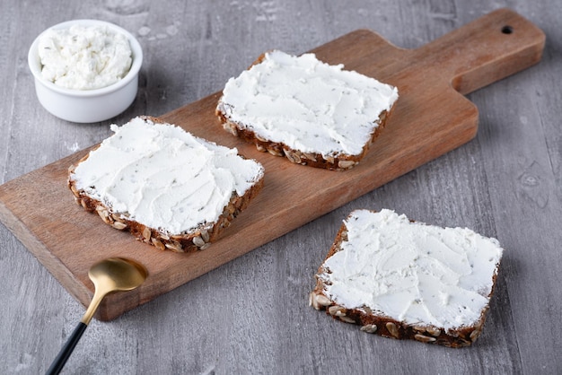 Hausgemachtes Roggenbrot auf einem Holzbrett mit Quark und Ricotta