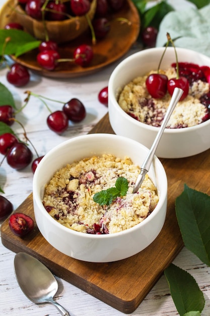 Hausgemachtes Sommerdessert Cherry Crumble in Auflaufform auf einer Holztischplatte