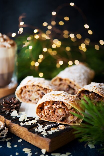 Hausgemachtes weihnachtsdessert, apfelstrudel, kuchen auf dem festlichen tisch mit girlanden, selektiver fokus