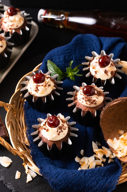 Hausmannskost-Konzept Hausgemachte Schwarzwälder Kokosnusscreme-Cupcakes auf blauer Serviette mit Kopienraum
