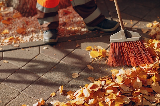 Hausmeisterreiniger fegt Herbstlaub auf der Straße