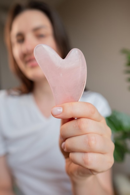 Hauspflege mit Gua Sha-Massagen für Frauen, um Schwellungen zu reduzieren und die Gesichtskonturen am Morgen aufzuheben